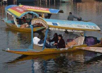 Tourists enjoy a serene Shikara ride on Dal Lake amidst crisp winter chill of January in Kashmir
